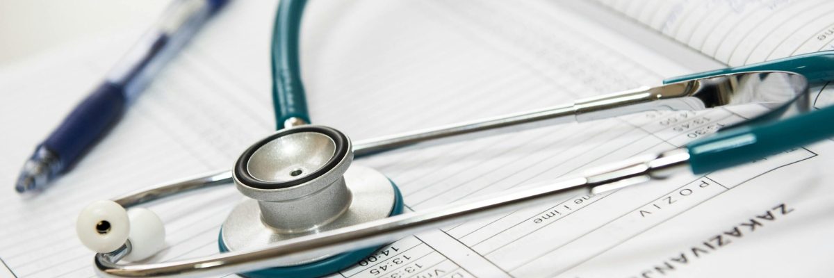 A stethoscope and pen resting on a medical report in a healthcare setting.